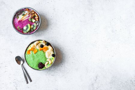 Colorful Smoothie Bowls for healthy detox breakfast, top view, copy space. Green spinach and berry smoothie bowls with various toppings. Vegan raw food, healthy eating concept.の写真素材