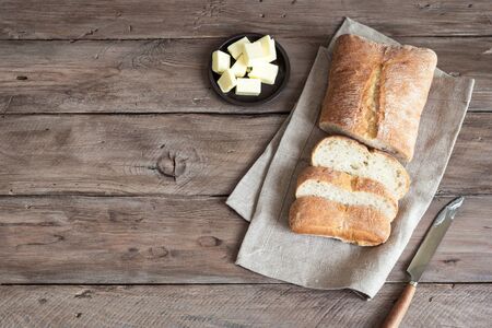 Bread and Butter on wooden table, copy space. Fresh ciabatta bread and organic butter for breakfast.