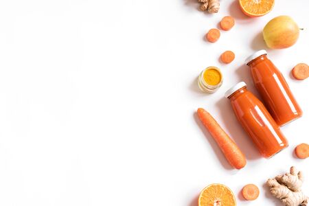 Detox cleanse drink, orange fruit and vegetable smoothie ingredients. Organic  juice in bottles. Carrot, apple, ginger, turmeric powder and orange mix isolated on white.の写真素材