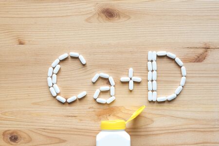 White pills forming shape to Ca D alphabet on wooden