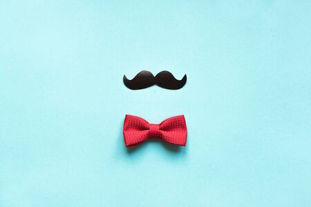 Father's Day or Hipster Concept flat lay. Creative composition with red bowtie and moustache on blue...