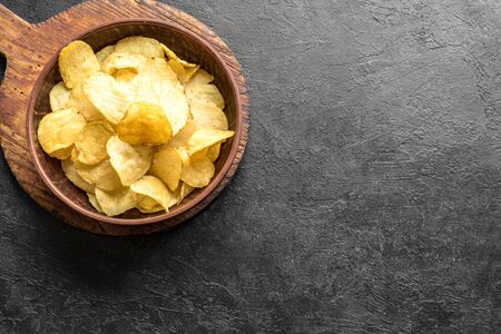Homemade potato chips in bowl. Crispy potato chips on black background, top view, copy space.の写真素材