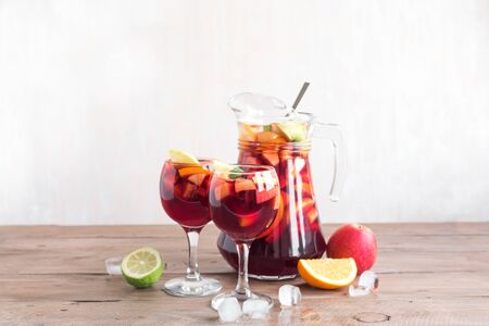 Red Wine Sangria in pitcher and glasses on wooden table, copy space. Homemade refreshing drink - fruit sangria or punch with ice.の写真素材