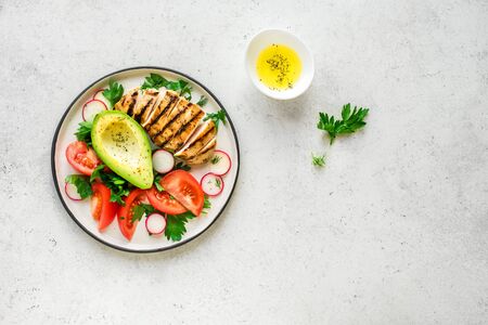 Healthy keto, ketogenic lunch menu with grilled chicken meat, avocado and organic veggies and greens. Roasted chicken breast, fillet and fresh vegetable salad, top view, copy space.の写真素材