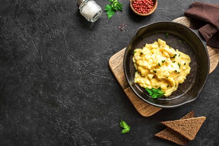 Scrambled Eggs on frying pan for healthy breakfast or brunch, top view, copy space. Homemade  meal recipe - scrambled eggs on black background.の素材 [FY310149712365]