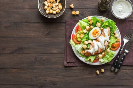 Caesar salad with chicken breast on dark wooden background, top view, copy space. Fresh chicken salad for healthy lunch.の写真素材
