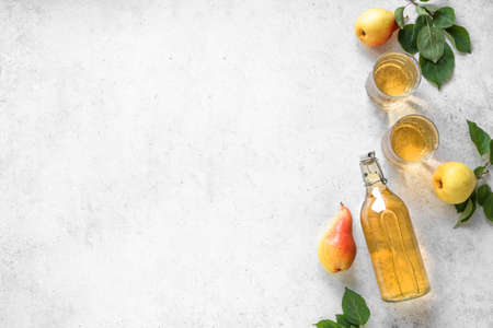 Pear cider drink or fermented fruit drink  in glasses and bottle and organic pears on white, top view, copy space. Healthy homemade hard pear cider recipe.の写真素材