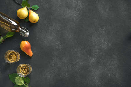 Pear cider drink or fermented fruit drink  in glasses and bottle and organic pears on black, top...