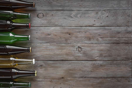 Assortment of beer bottles on dark wooden background, top view, copy space. Fresh cold beer for choice. Various sorts of beer.の写真素材