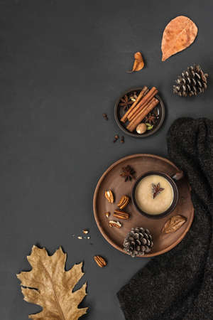 Autumn spicy hot drink, soft plaid and leaves creative flat lay. Fall Background. Dried leaves, pine cones and coffee or tea on black, Thanksgiving day, hygge cozy concept, top view, copy space.の写真素材