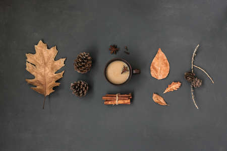 Autumn Leaves and cup of hot drink creative flat lay. Fall Background. Dried leaves, pine cones and coffee or tea on black, Thanksgiving day cozy concept, top view, copy space.の写真素材