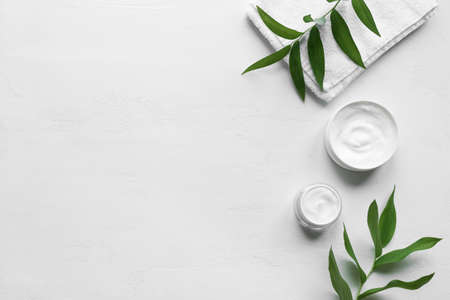 Natural skin care - cosmetic hygienic cream with towel and green plants on white background, top...