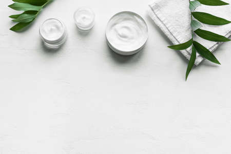 Natural cosmetic hygienic cream with towel and green plants on white background, top view, copy space. Dermatology, organic skin care concept with green leaves, banner.の写真素材