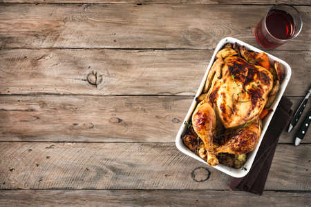 Roasted chicken or turkey with vegetables and glass of wine for festive dinner. Grilled chicken on wooden table, top view, copy space.の写真素材