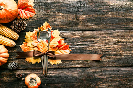 Autumn Thanksgiving Table Setting. Cutlery and autumn leaves on wooden table with pumpkins and autumn decor, copy space. Thanksgiving holiday menu concept.の写真素材