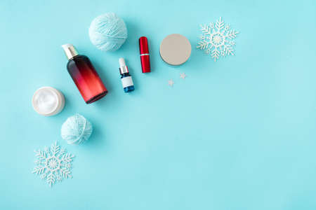 Winter Skin Care products and snowflakes on blue background, flat lay, copy space. Seasonal beauty routine and skin protective cosmetic for winter weather concept.の写真素材