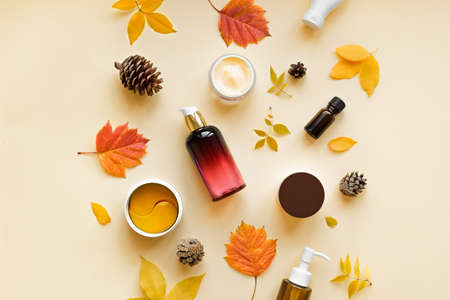 Autumn Skin Care products and autumn leaves on yellow background, flat lay, copy space. Seasonal beauty routine and organic skin care concept.の写真素材
