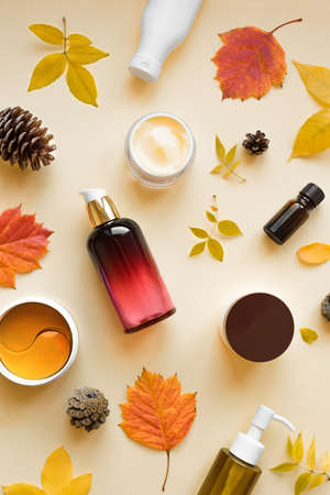 Autumn Skin Care products and autumn leaves on yellow background, flat lay, copy space. Seasonal beauty routine and organic cosmetic concept.の写真素材