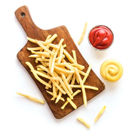 French fries on board with ketchup and cheese sauce isolated on white background. Homemade french...