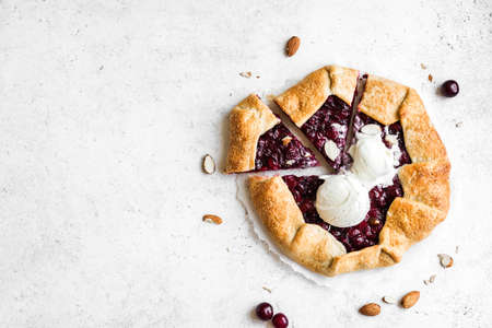Cherry Galette with almonds and vanilla ice cream on white table, top view, copy space. Homemade healthy dessert - cherry pie or french galette.の写真素材