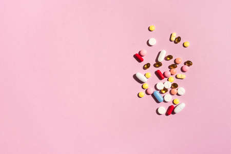 Multicolored tablets, pills, capsules on pink background, copy space. Heap of assorted various medicine tablets and pills, vitamin and nutritional supplements concept.の写真素材