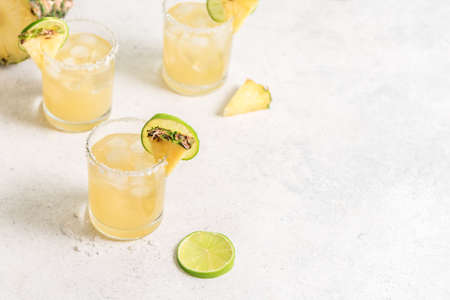 Pineapple Margarita Cocktail. Summer boozy refreshing drink with tequila, pineapple in glasses with...