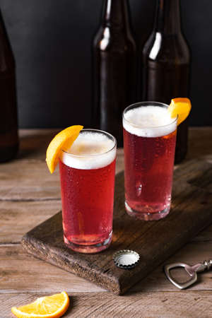Grapefruit or Cherry Radler, citrus beer cocktail. Refreshing fruit beer drink on dark table, copy...