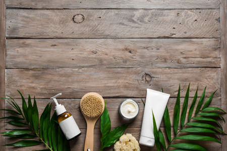 Natural skin care products, massage brush and green leaves on wooden, top view, copy space. Natural eco beauty and organic skin care concept.の写真素材