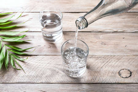 Water pouring into glass. Glass of water on wooden table, selective focus, close up. Clear purified water for drink.の写真素材