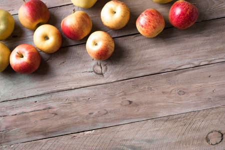 Apples on wooden background, top view, copy space. Garden organic red and yellow apples border.