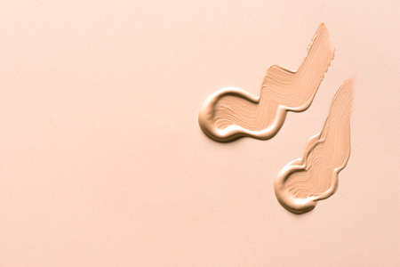 Liquid make up base swatch on beige background. Sample of cc, bb cream, corrector or liquid base cream smear.の写真素材