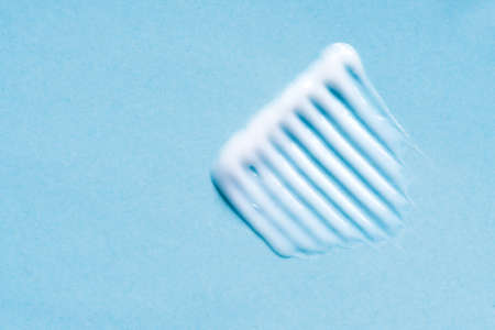 Face or body cream hair balm swatch on blue background, close up. Stroke of cosmetic product.