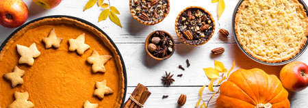 Thanksgiving autumn pies on white wooden background, banner. Fall homemade pumpkin, apple and pecan pies and ingredients for autumn holidays.の写真素材
