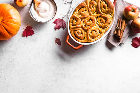 Autumn pumpkin apples cinnamon rolls and organic pumpkins and apples on white background, top view, copy space. Seasonal autumn homemade pastry - cinnabons for breakfast.の写真素材
