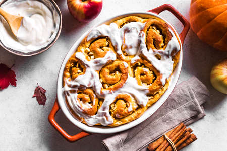 Pumpkin apples cinnamon rolls and organic pumpkins and apples close up. Seasonal autumn homemade pastry - cinnabons for breakfast.の写真素材