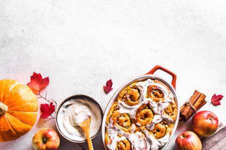 Pumpkin apples cinnamon rolls and organic pumpkins and apples on white background, top view, copy space. Seasonal autumn homemade pastry - cinnabons for breakfast.の写真素材