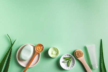 Aloe vera plant leaves, gel, skin care products on green, top view, copy space. Natural organic aloe vera cosmetics for face and body care.の写真素材
