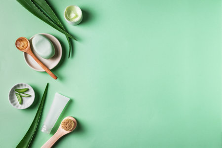 Aloe vera plant leaves, gel, skin care products on green, top view, copy space. Natural organic aloe vera cosmetics for face and body care.の写真素材