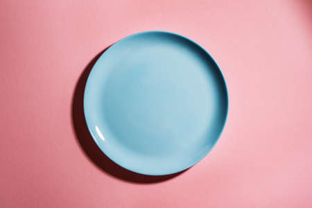 Blue empty plate on pink pastel background, top view, copy space. Cooking and eating healthy food concept, meal design mock up.の写真素材