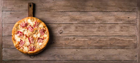 Bacon Pizza. Italian Carbonara Pizza with bacon and mozzarella cheese on wooden table, top view, copy space, banner.の写真素材