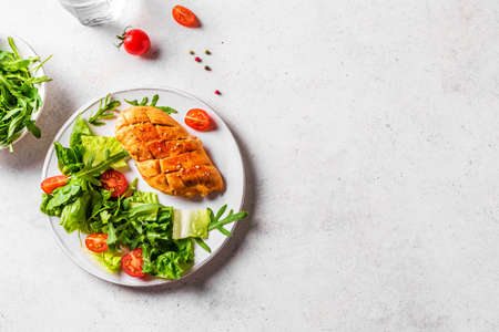 Chicken Salad with fresh vegetables and greens on a white table. Roasted Chicken Fillet, green...