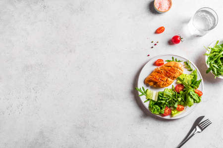 Chicken Salad with fresh vegetables and greens on a white table. Roasted Chicken Fillet, green lettuce, arugula, tomatoes salad for healthy lunch, top view, copy space.の写真素材
