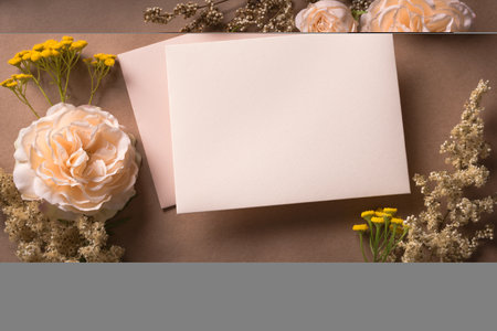 Greeting or invitation blank card, rose flowers on craft brown background, copy space. Stylish creative autumn fall mock up, autunm holiday celebration concept.の写真素材