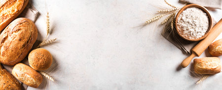 Assortment of various delicious freshly baked bread and flour ingredient on white background, banner, copy space. Variety of artisan bread and ears of wheat.の写真素材