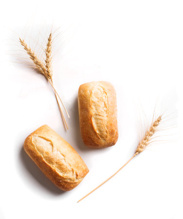 Fresh homebaked artisan bread. Two mini baguette bread and ears of wheat isolated on white background, design element.の写真素材