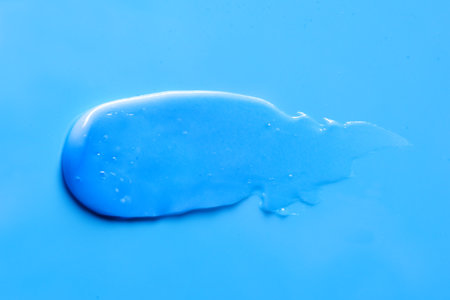 Blue skincare product smear of toothpaste or face mask on blue background. Blue cosmetic cleanser texture skincare lotion swatch. Face peeling, body moisturizer, tint hair conditioner smudge stroke.の写真素材