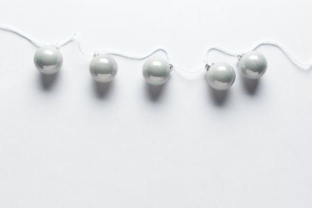 Christmas background. Christmas Silver Balls on a String, layout on white background, top view, copy space. Trendy holiday concept.の写真素材