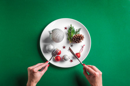 Creative Christmas Table Setting and female hands. Festive silver baubles and pine cone on white...