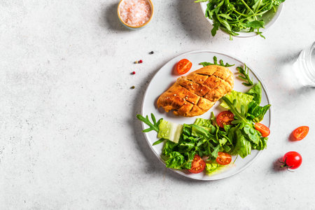 Chicken Salad with fresh vegetables and greens on a white table. Roasted Chicken Fillet, green lettuce, arugula, tomatoes salad for healthy lunch, top view, copy space.の写真素材