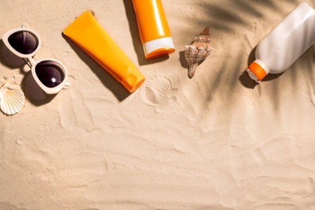 Sunblock lotion bottles, sea shells and sunglasses on sandy beach, copy space. Summer vacation and skin care concept, sunscreen, spf uv-protect cosmetics.の写真素材